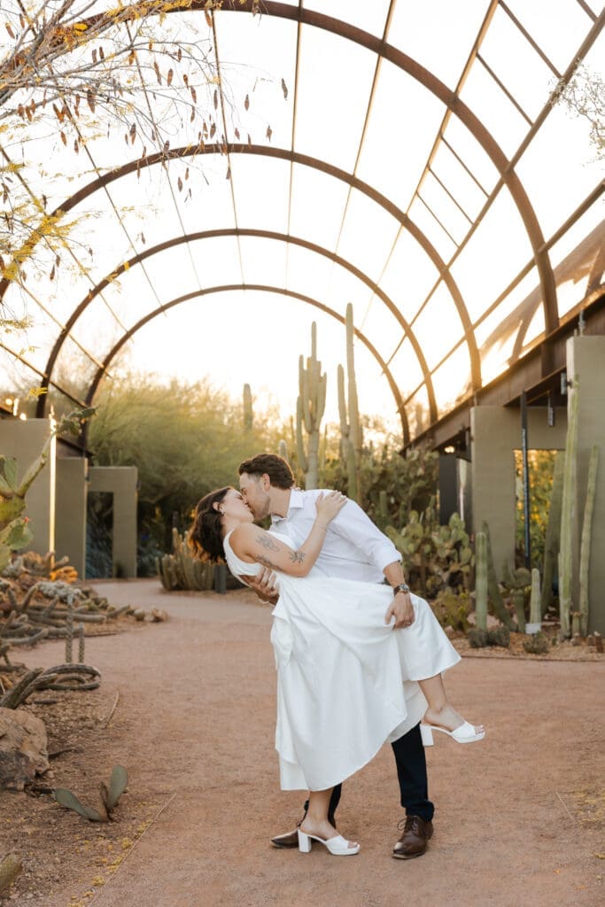 Romantic kiss dip photo with arching glass dome architecture. 