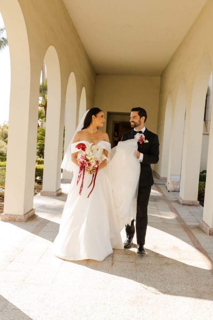 Bride and groom walking through arched hallways after wedding ceremony.