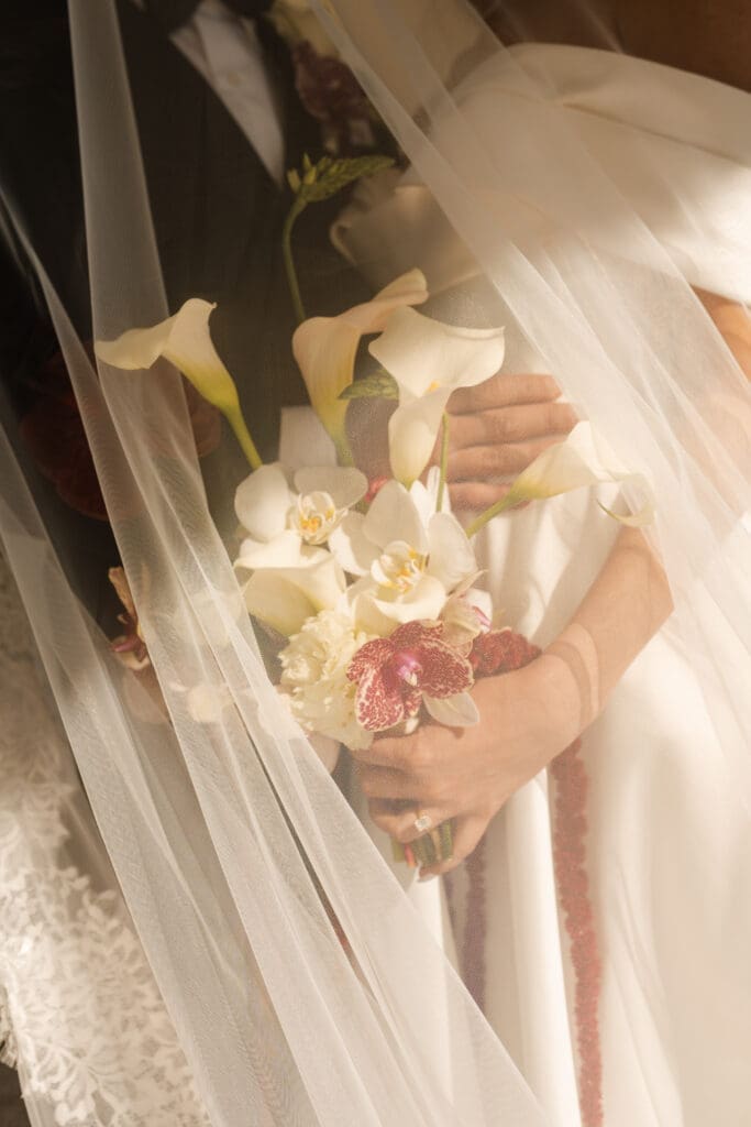 Bridal bouquet nestled under bride's veil.