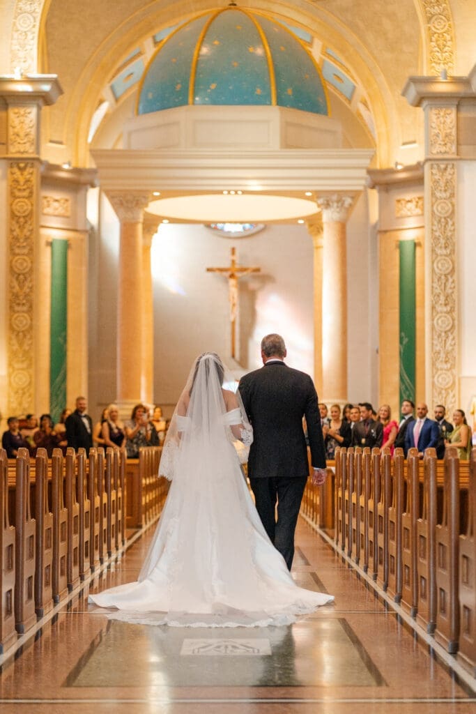 Father walking bride down the aisle in Immaculata Catholic Church.