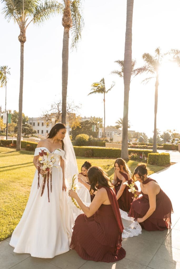 Bridesmaid and bridal party fixing bride's dress